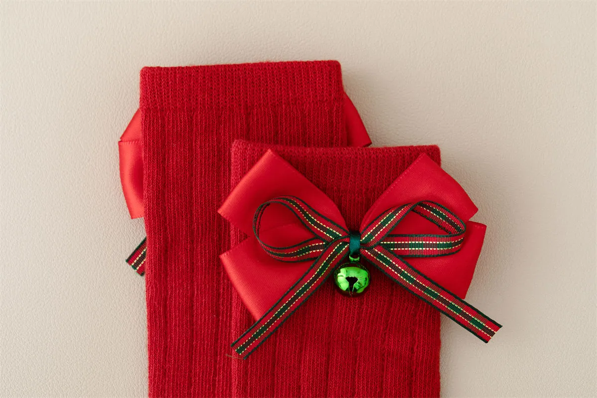 Close-up of red cotton knit baby socks with a festive bowknot and green jingle bell. Close-up of red cotton knit baby socks with a festive bowknot and green jingle bell.