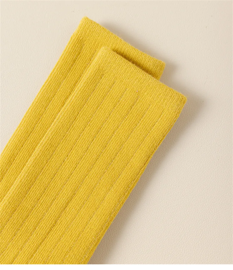 Yellow cotton knit baby socks texture detail showing soft ribbed fabric.
